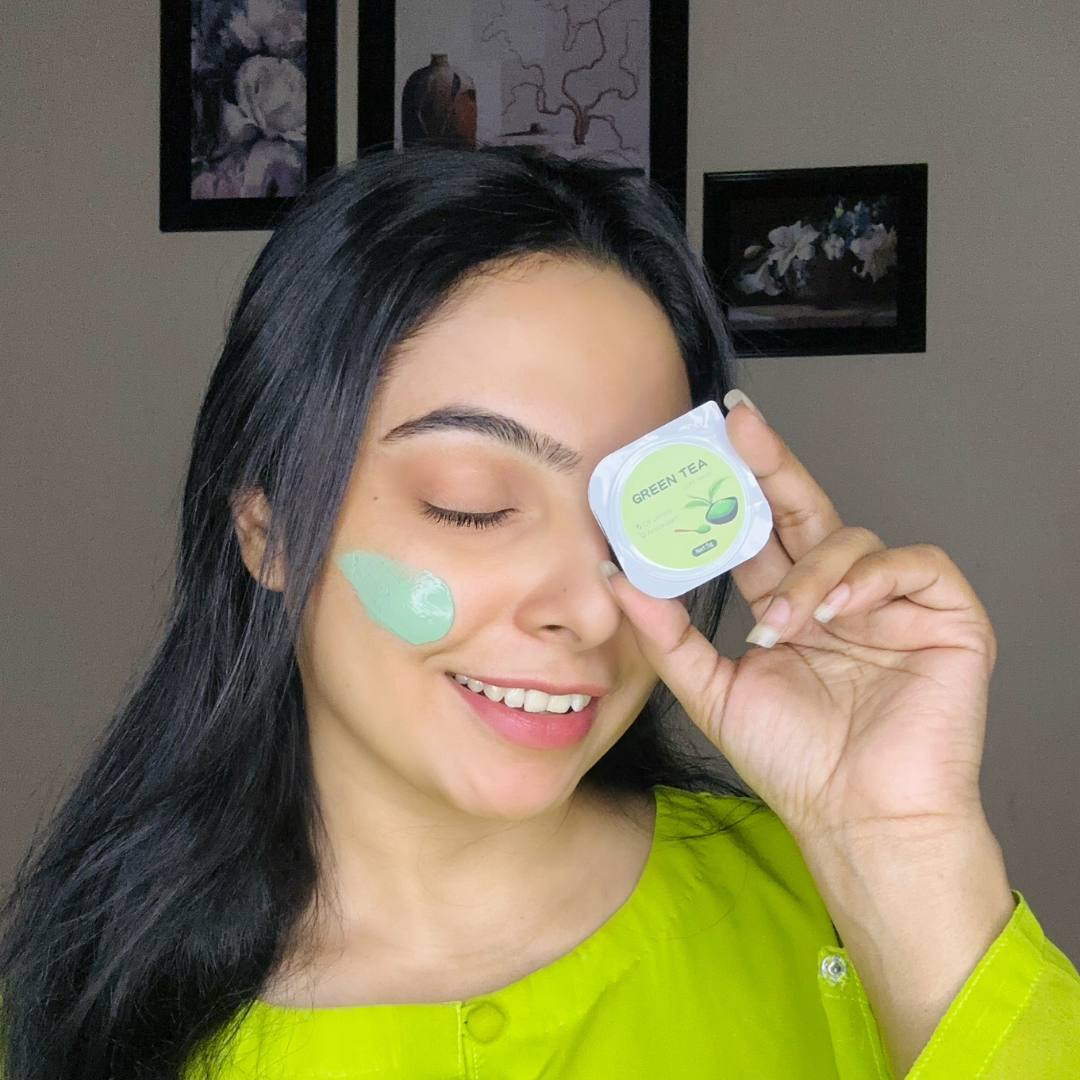DHEO Glow Pop Green Tea Facial Mask pod held by a smiling model