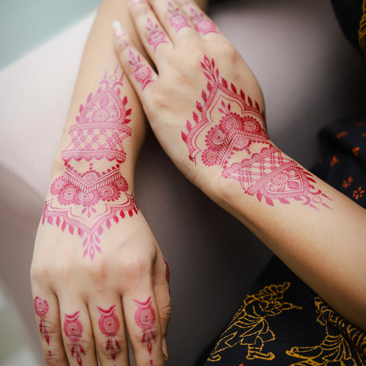 Close-up of hands with pink henna designs on a blurred background