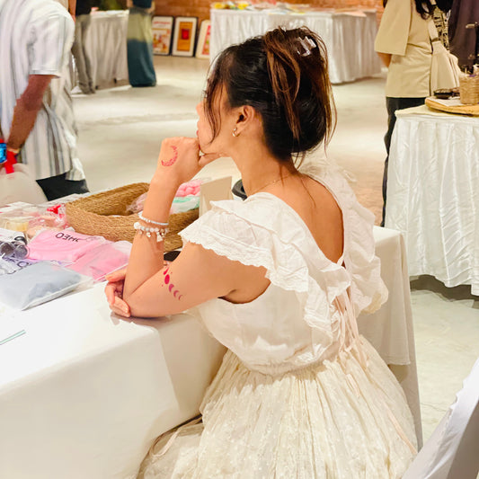 Woman in a white dress sitting at a table with a blurred indoor background