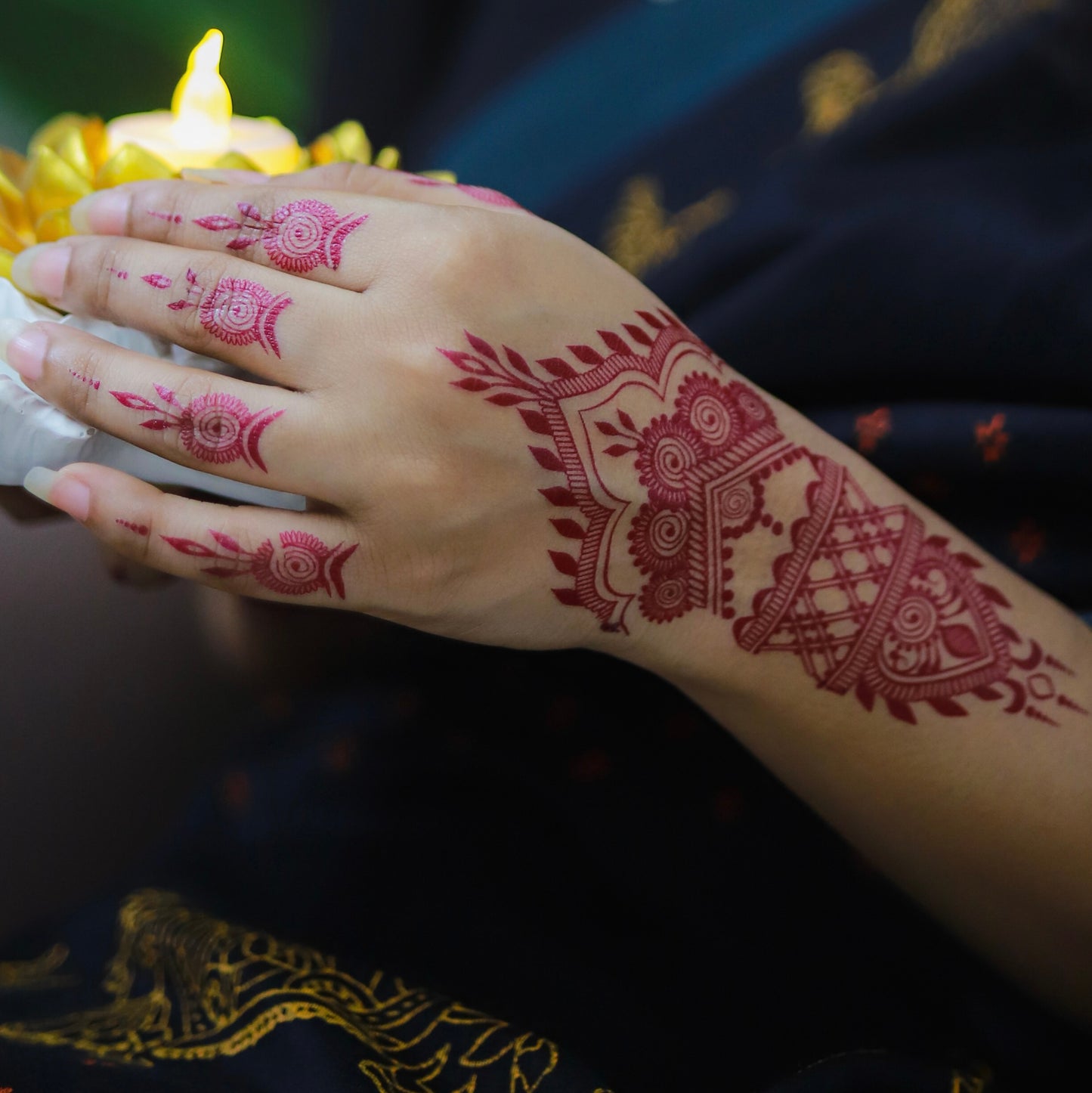 Hand with intricate red henna designs against a dark background