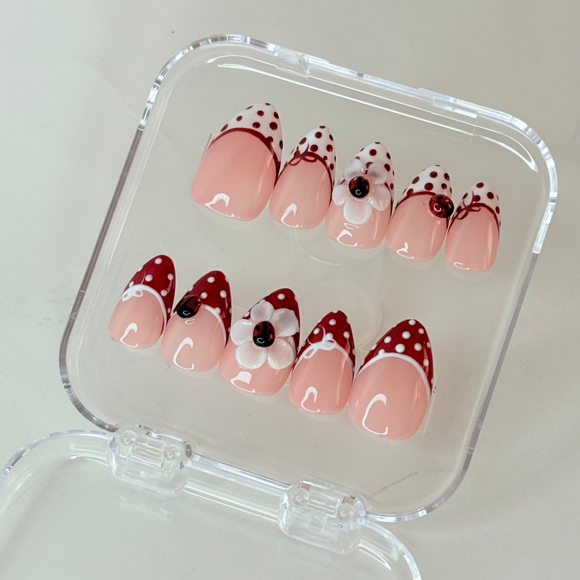 Ladybug Garden press-on nails flat-lay showing red with ladybug and leaf art
