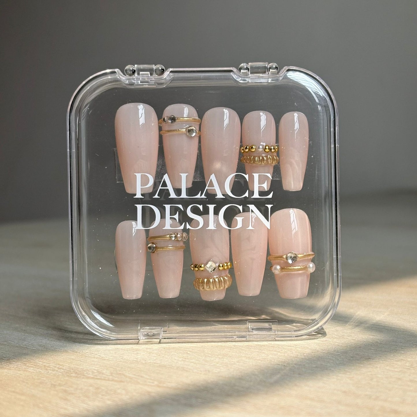 Crowned Glory press-on nails worn on hand showing elegant gold detailing on cream
