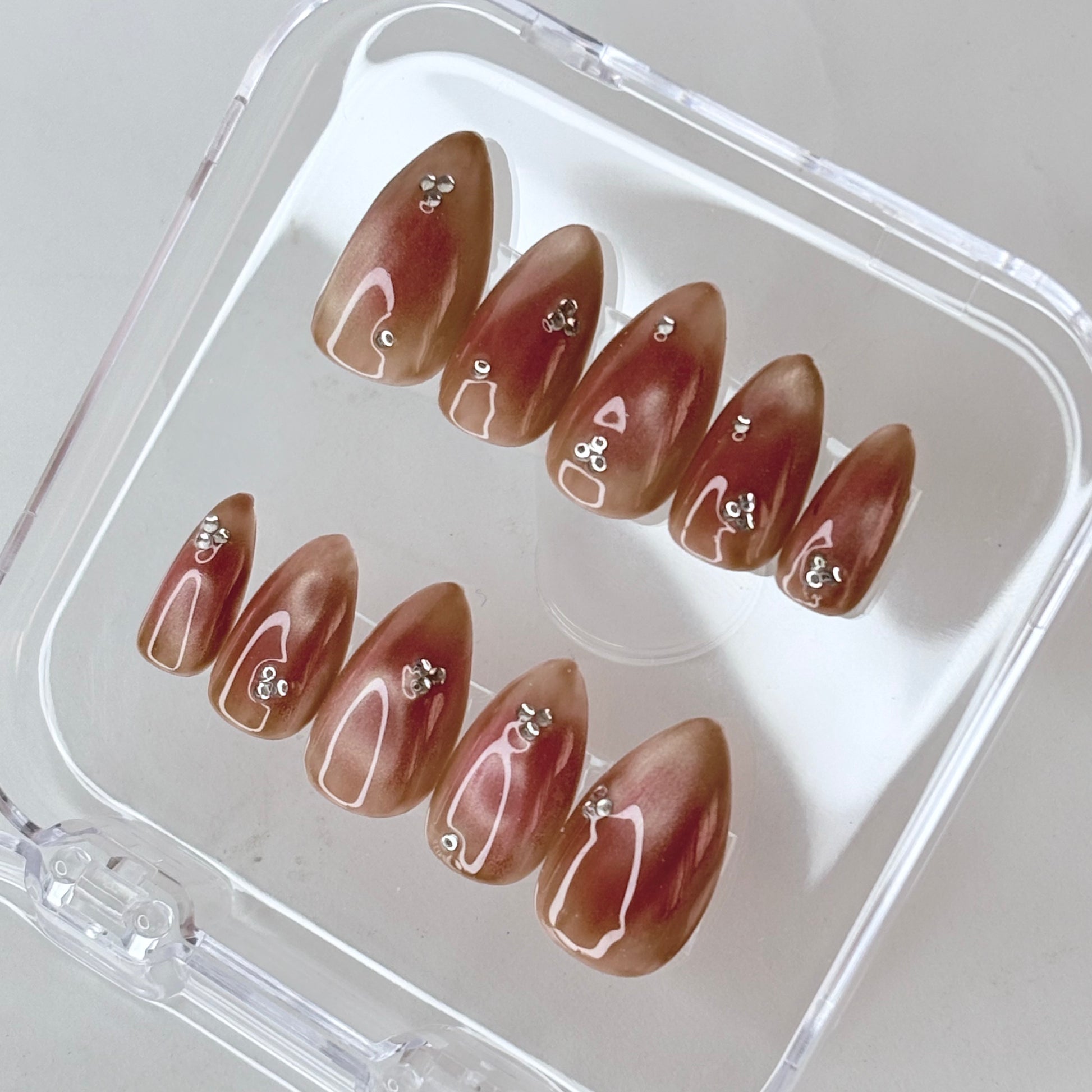 Burnt Sugar press-on nails flat-lay showing warm amber brown with caramel gloss